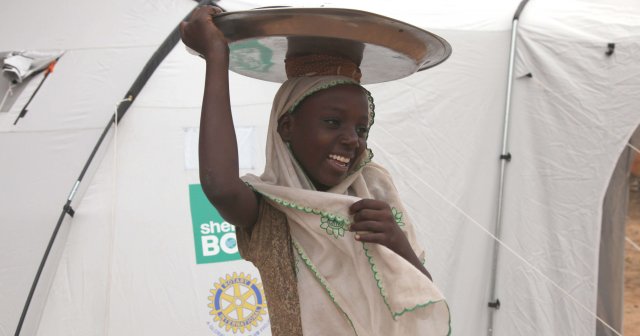 Girl carrying a tray upon her head from Niger smiling