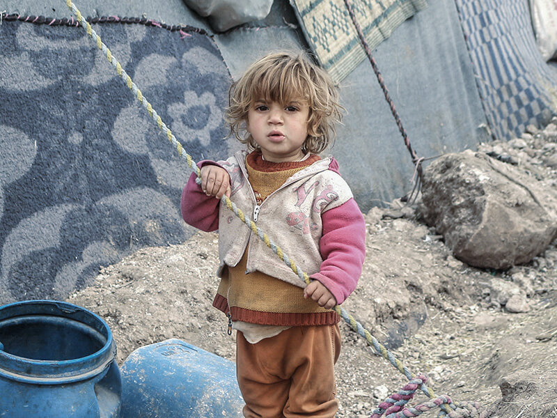 Girl stands alone in refugee camp Syria