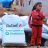girl with folded arms stands with shelterbox and reliefaid aid