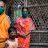 Two women and a child wearing face masks and standing outside their home.