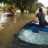 Man sat on top of his car with the road around him flooded