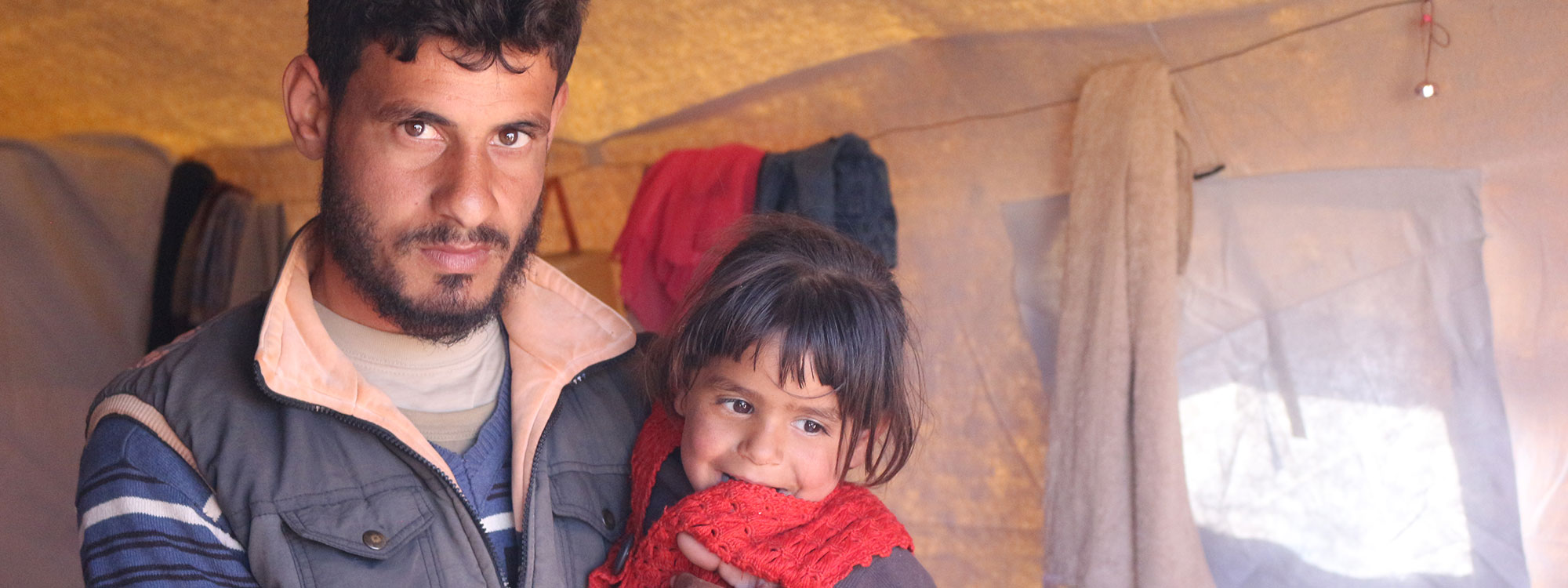 man and daughter in displacement camp syria