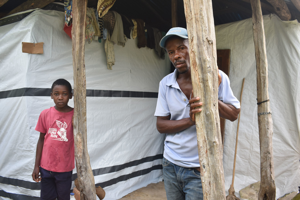 A man and a boy outside a makeshift shelter