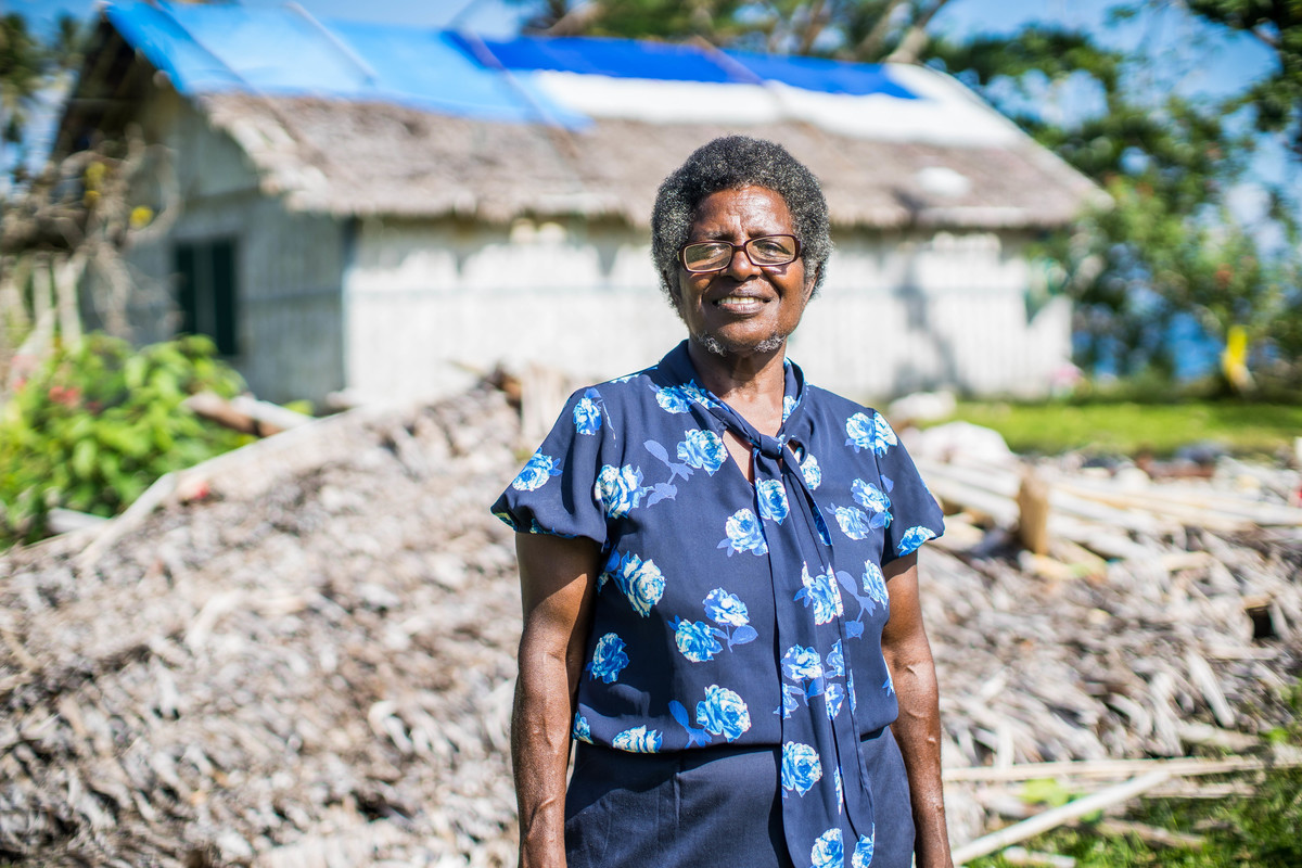 woman standing in front of a damaged home in Vanuatu