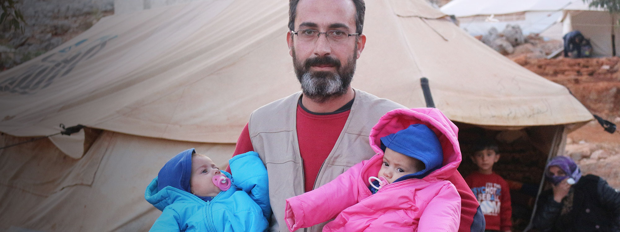 Syrian man carries two babies in snowsuits