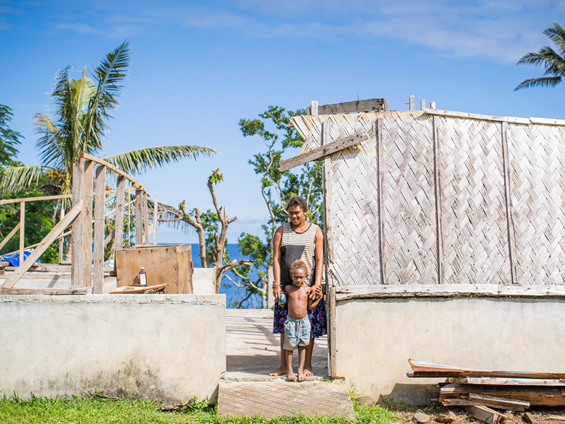 woman and child stand in destroyed home after cyclone harold hit vanuatu