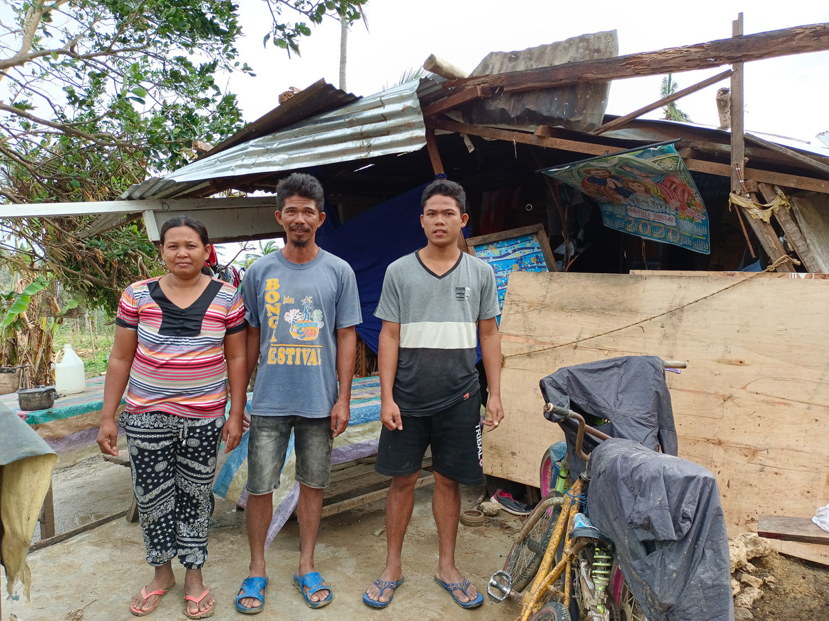 Three people standing in front of a makeshift shelter